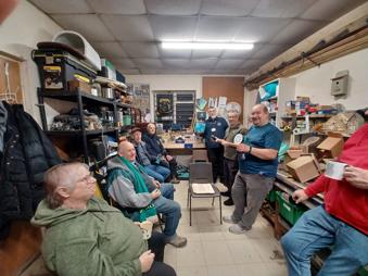 Eight adults together as part of Swanley's shed - some sitting, some standing.